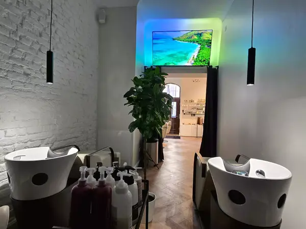 Moderner Friseursalon mit Waschbecken, Pflanzen und TV mit Strandbild