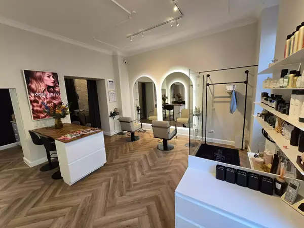 Moderner Friseursalon mit Stylingstühlen, Spiegeln, Rezeption und Produkten.