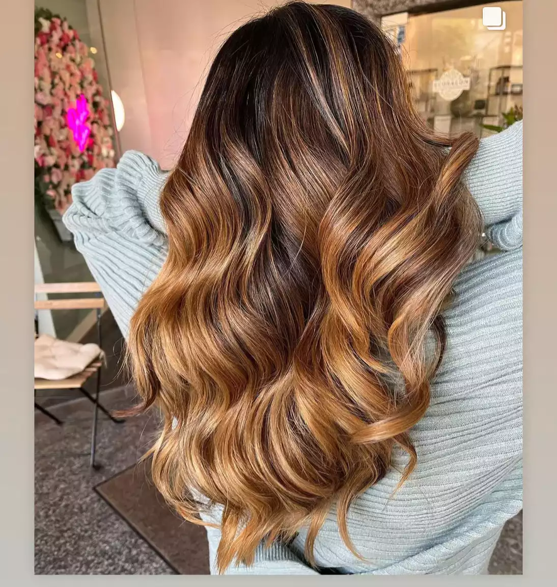 Lange, wellige Balayage-Haare in Braun mit karamellblonden Highlights.