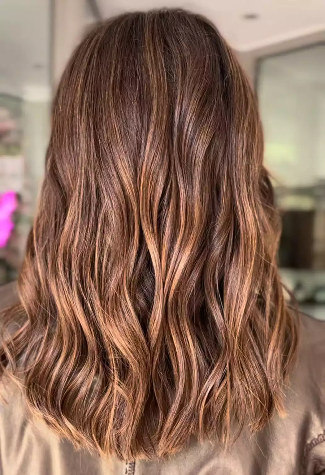 Welliges braunes Haar mit karamellfarbenen Balayage-Highlights im Salon
