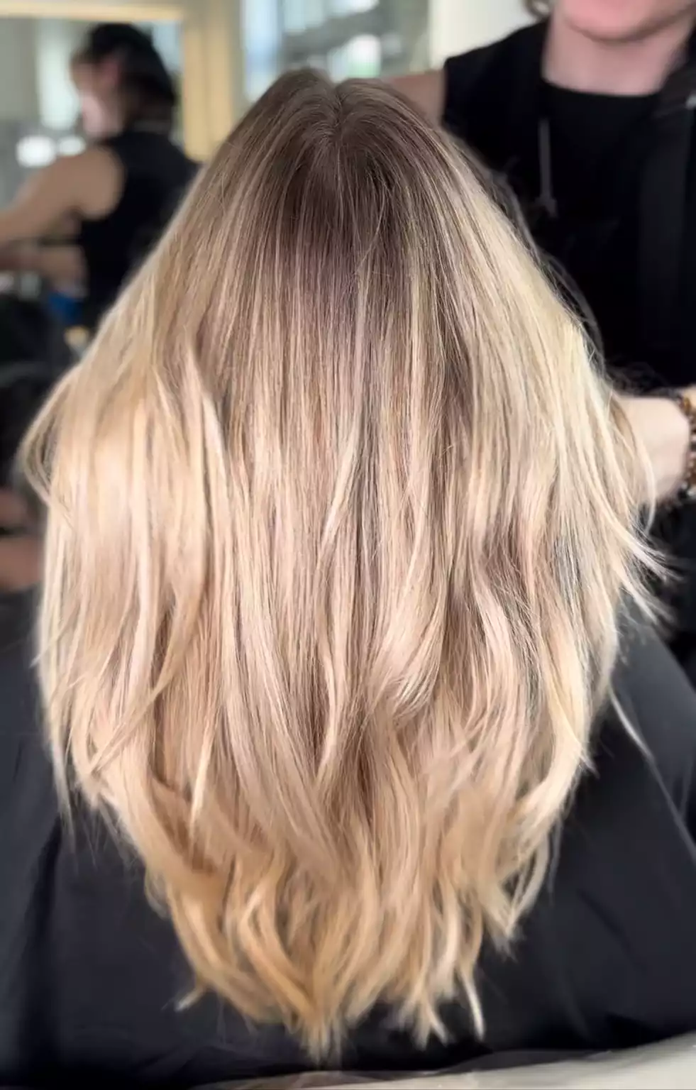 Balayage Blond mit dunklem Ansatz, wellige mittellange Haare im Salon