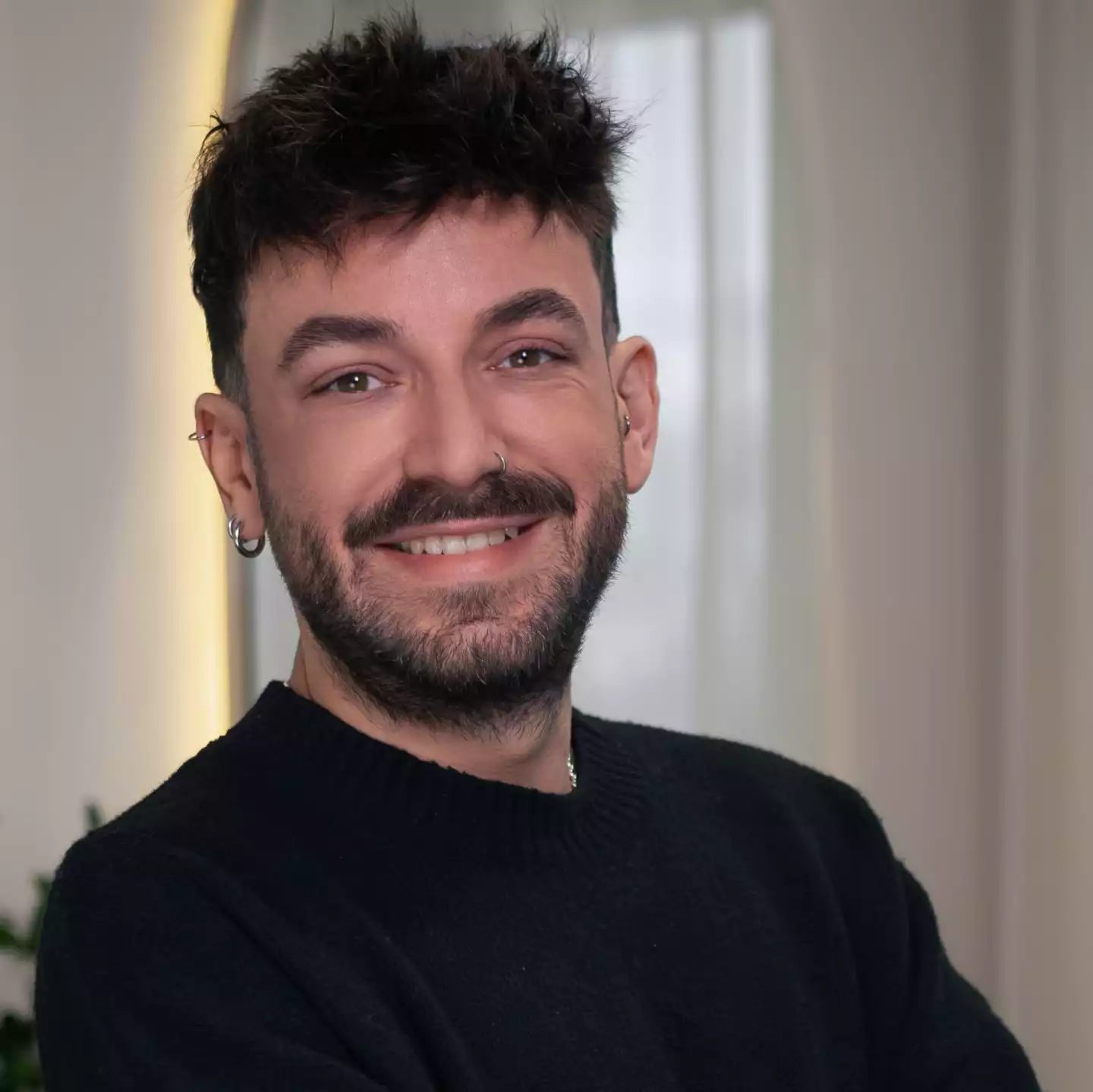 Porträt eines lächelnden Mannes mit Bart und Piercings im Innenraum